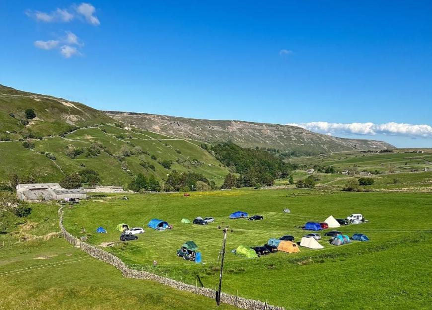 Pepper Hall campsite with tents and cars in a field.