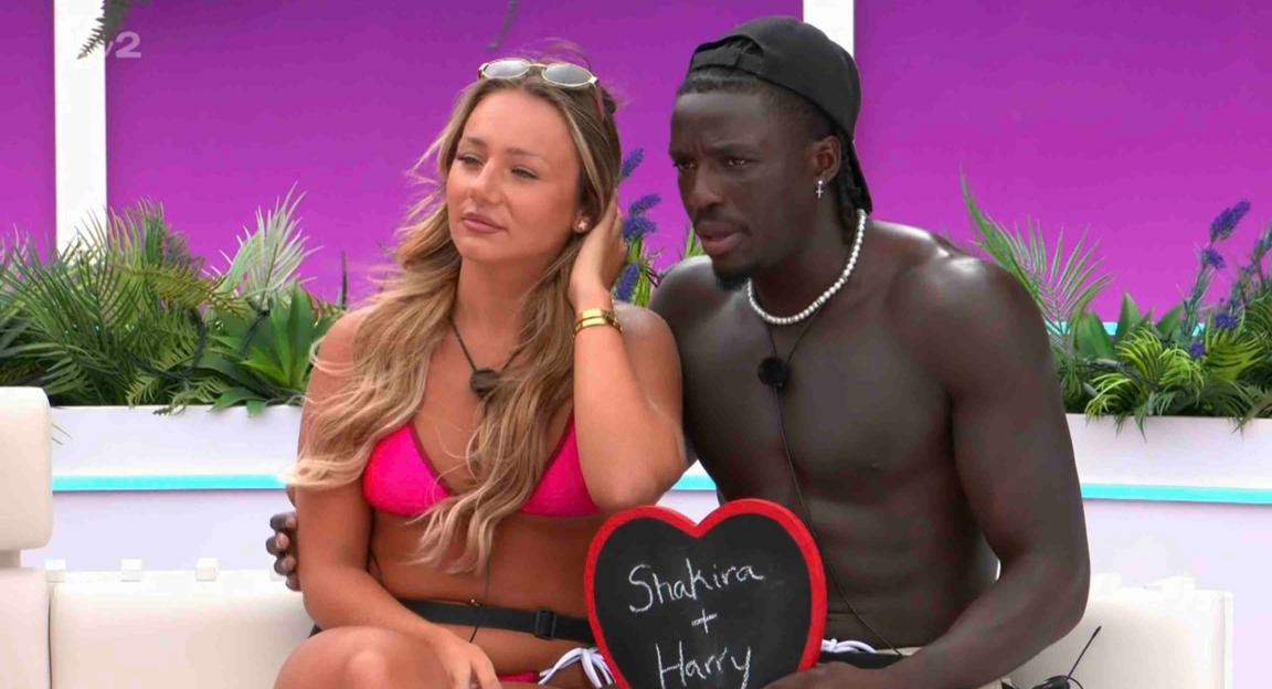 Shakira and Harry from Love Island holding a heart-shaped chalkboard that says 