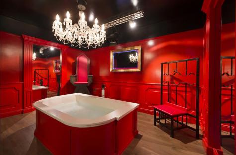 Interior of a red-themed room with a bathtub, a chair, and a bench.