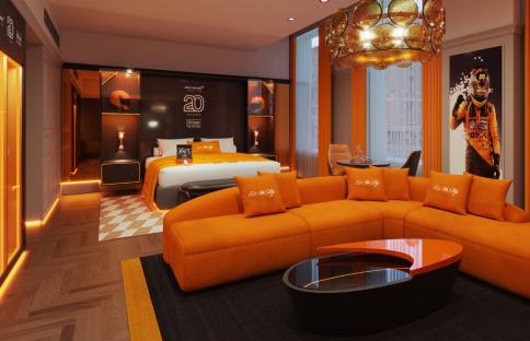 Illustration of a McLaren-themed Hilton hotel suite, including a closet with racing gear and a living area with orange furniture.