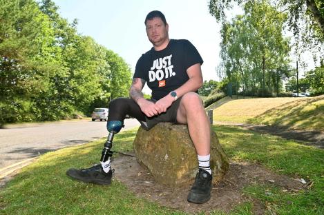 Man with prosthetic leg sitting on a rock.