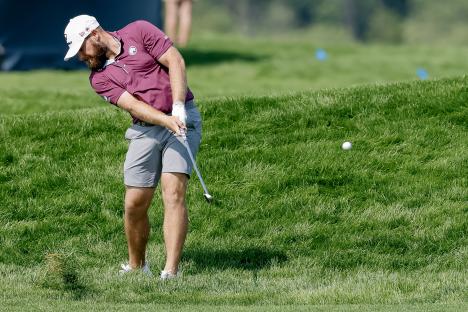 Matt Vogt hitting a golf ball from the rough.