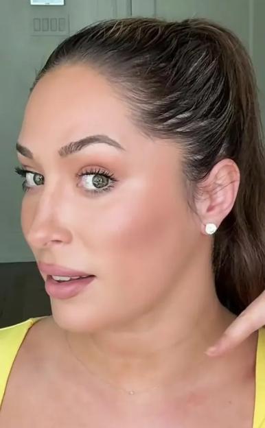 Woman demonstrating bronzer application for a lifted jawline.