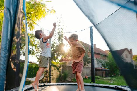 Two boys joyfully jumping on a trampoline outdoors.