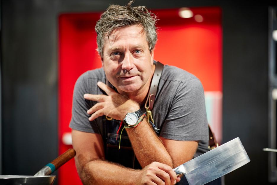 Portrait of John Torode holding a large knife.