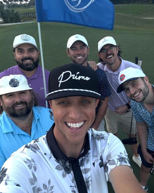 Group selfie of six men on a golf course.