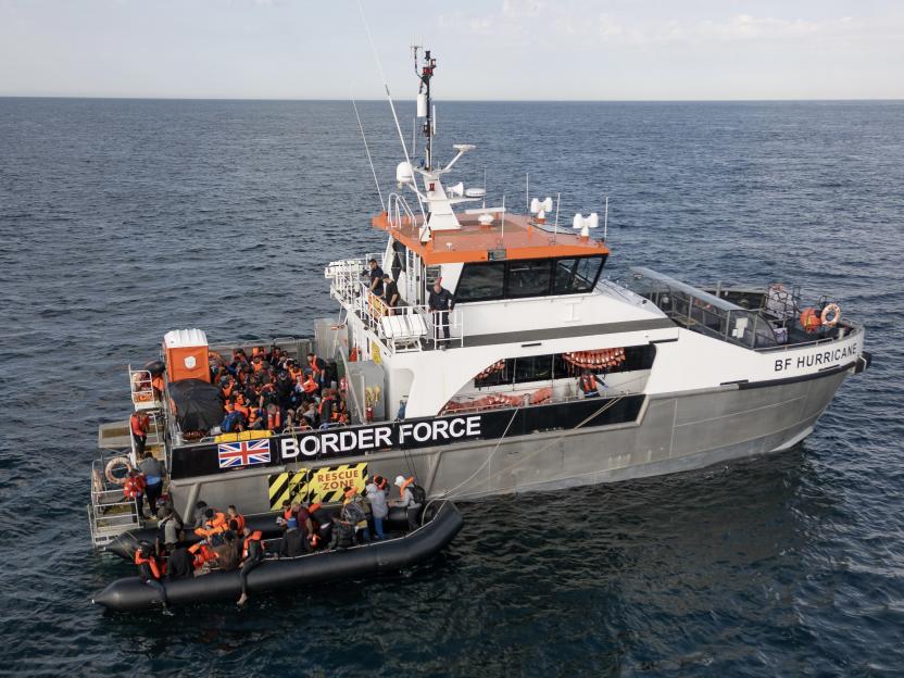 A Border Force vessel rescuing migrants from a small inflatable boat.