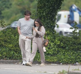 Jack Fincham and Chloe Brockett walking and looking at a phone.