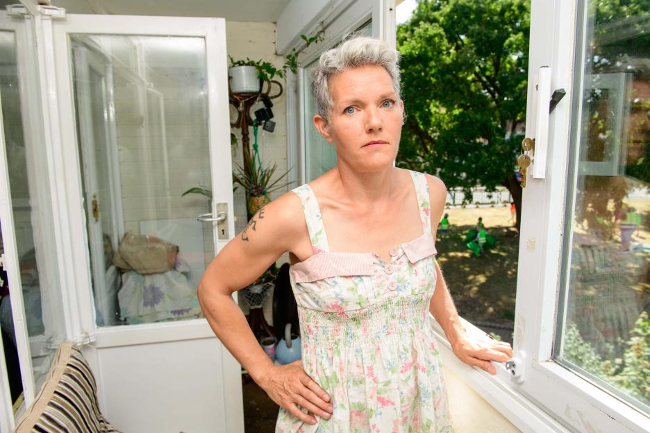 Woman standing on a balcony, looking concerned.