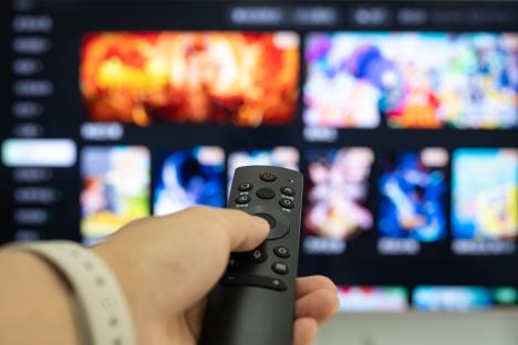 Hand holding a TV remote, changing channels.
