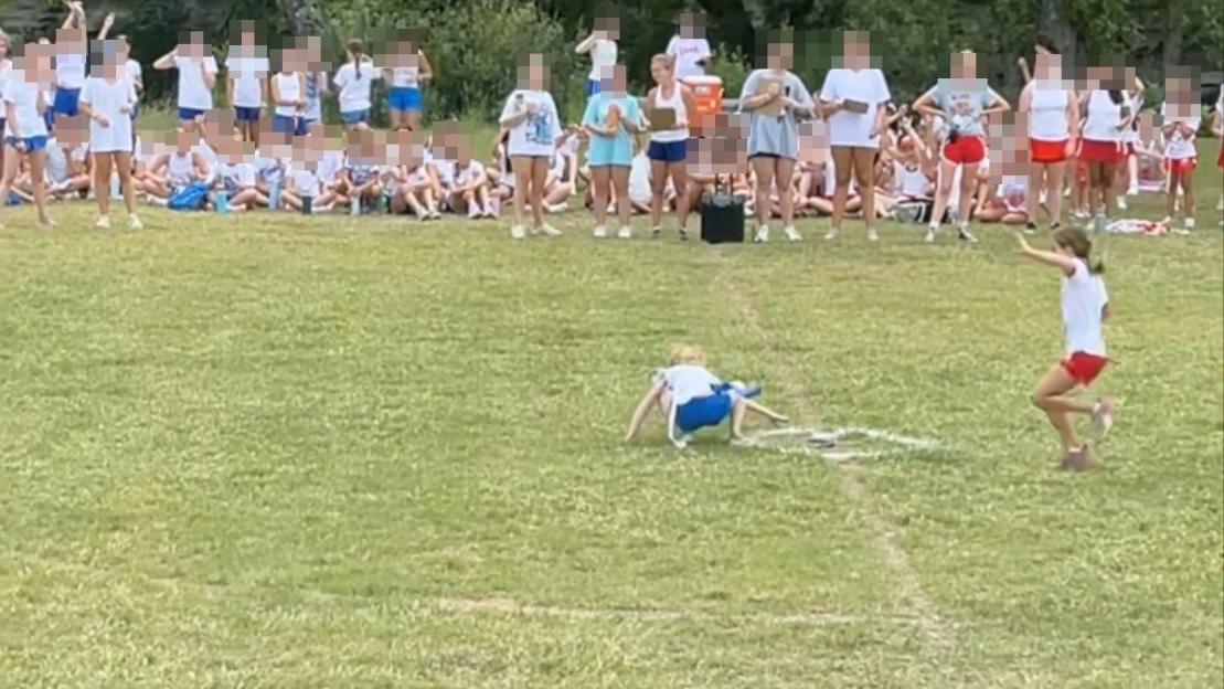A girl falling during a field day event while other girls watch.