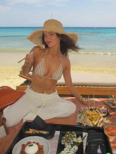 Woman in bikini eating on Mykonos beach.