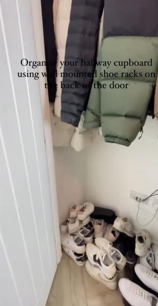 Shoes piled on the floor and organized with wall-mounted shoe racks on the back of a door.