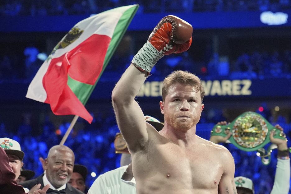 Canelo Ãlvarez celebrates a victory, raising his arm and a championship belt.