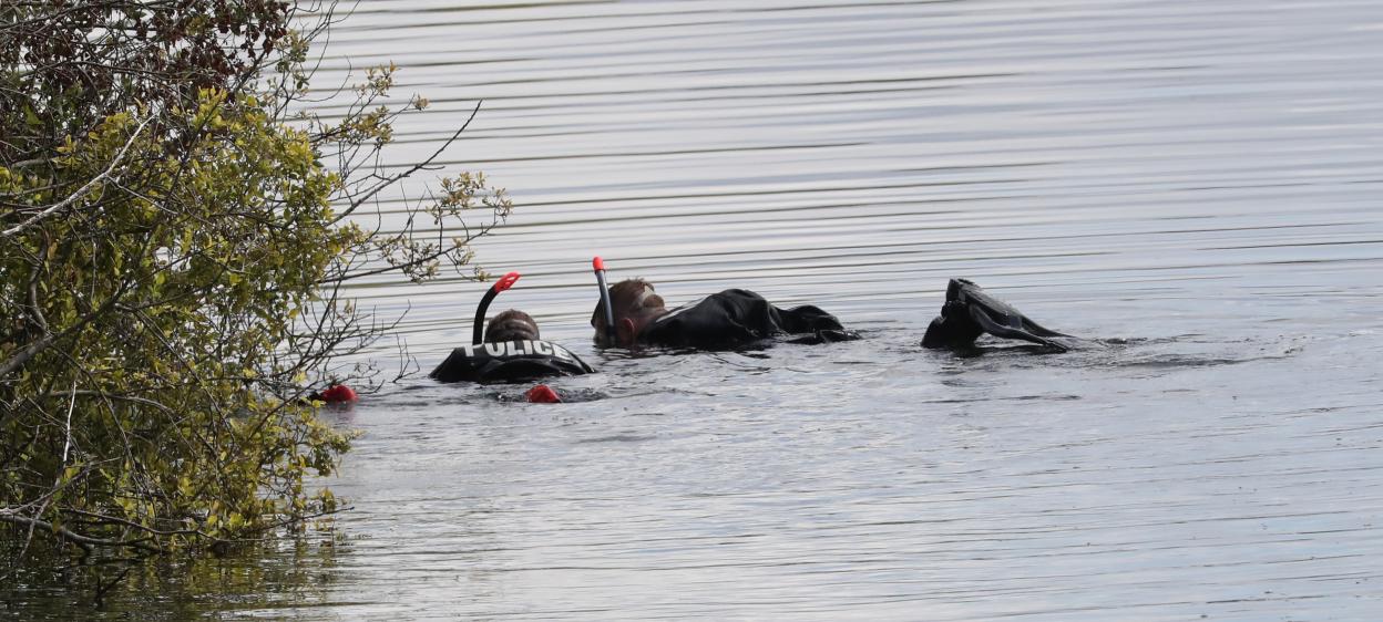 Police divers searching a lake.