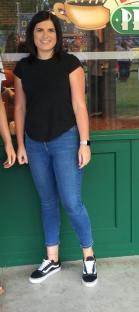Woman in black shirt and jeans standing in front of a green door.
