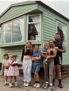 Family of seven posing in front of their new caravan.