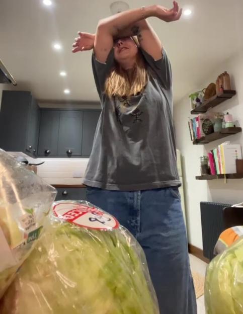 Woman overwhelmed by large amount of lettuce from a grocery bag.