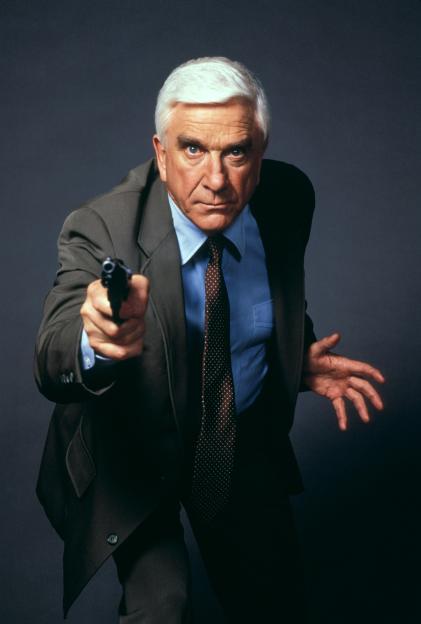 Leslie Nielsen pointing a gun in a suit.