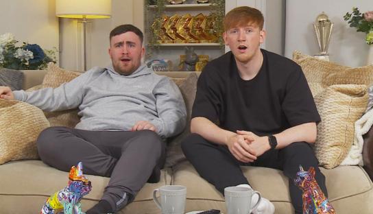 Two men sitting on a couch, announcing their participation in a reality TV show.