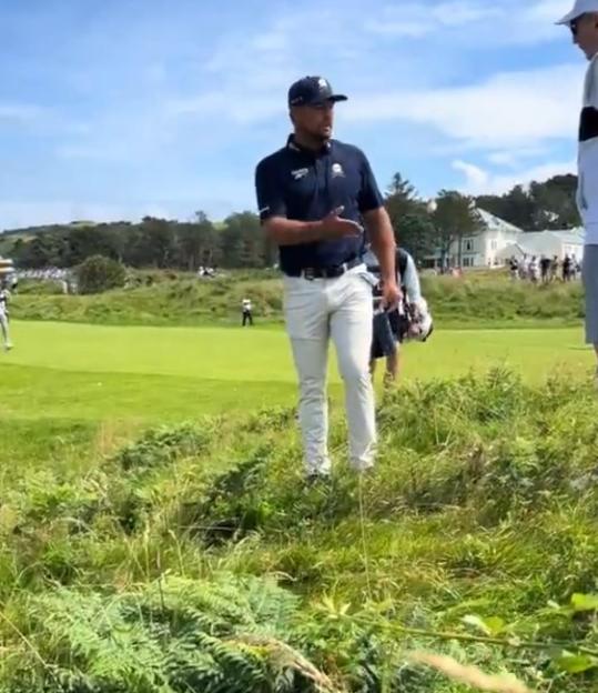 Golfer talking to someone on a golf course.