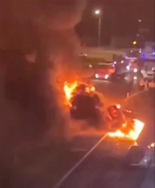 Burning car on a road at night.