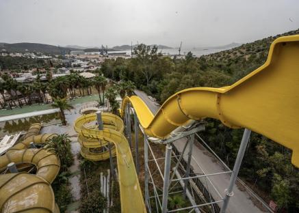 Overgrown abandoned water park with yellow slides.