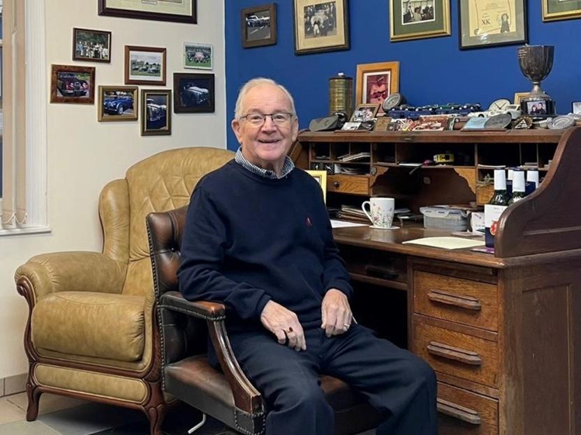 Photo of John Brown, a Jaguar restoration expert, sitting in his home office.