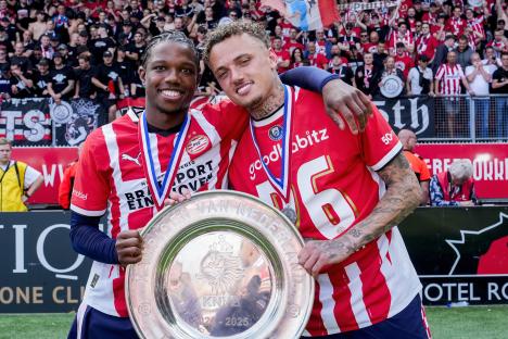 PSV Eindhoven players celebrating Eredivisie championship with trophy.