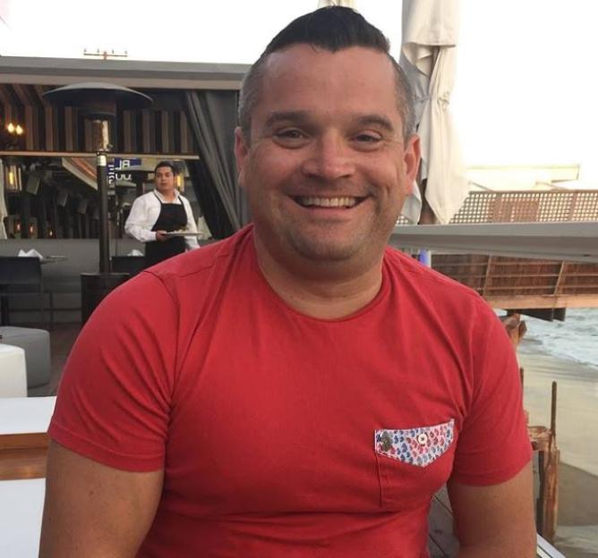 Louis Osbourne, son of Ozzy Osbourne, smiling while wearing a red t-shirt.