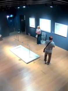 High-angle view of two people in an art gallery near a damaged art installation.