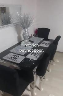 Dining table with black chairs and a sparkly Chanel-logo tablecloth.