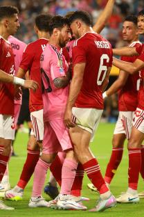 Lionel Messi and another soccer player facing each other on the field.
