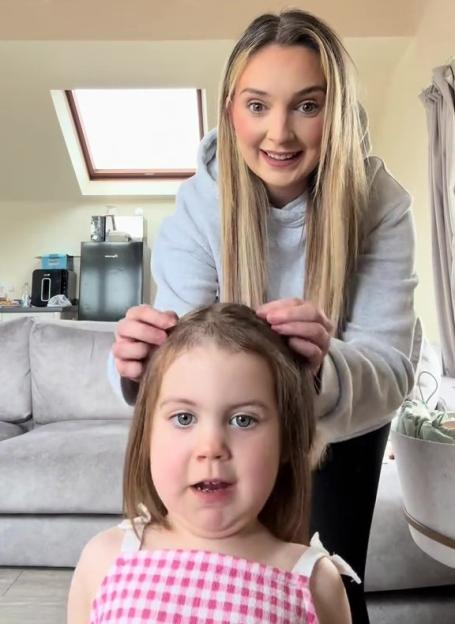 A woman styling her young daughter's hair.
