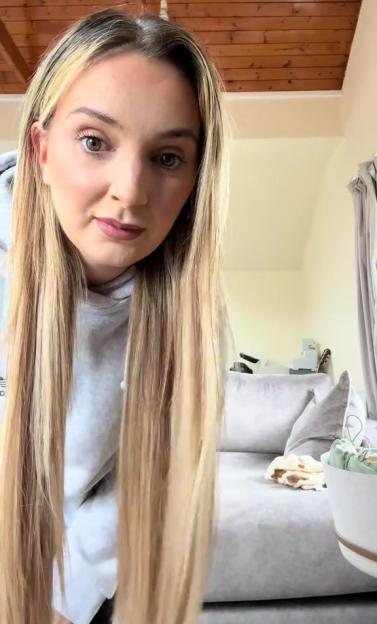 A blonde woman in a grey sweatshirt reacting to a toddler's bad haircut.