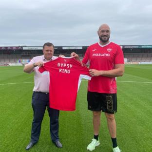 Tyson Fury holding a Morecambe FC jersey.