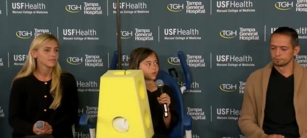 A 9-year-old girl, her mother, and father at a press conference.