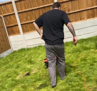 Person walking on a patchy lawn with a lawnmower.