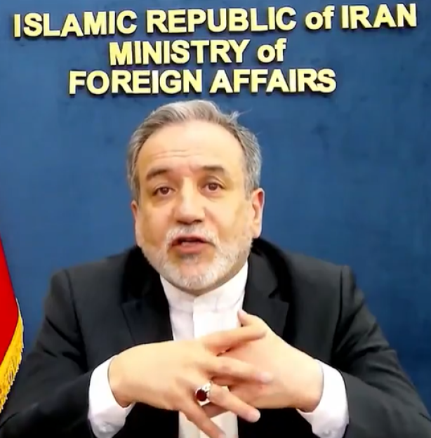 A man speaking in front of an Iranian Ministry of Foreign Affairs sign.