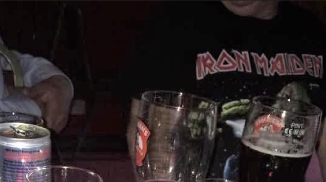 Person wearing an Iron Maiden t-shirt with drinks in front.