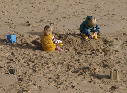 Two young children building sandcastles on a beach.