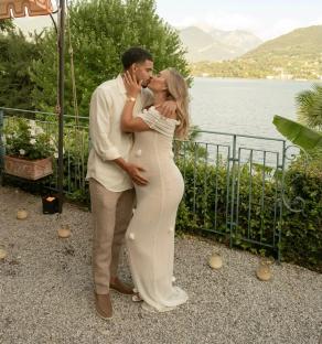 Pregnant couple kissing by a lake.