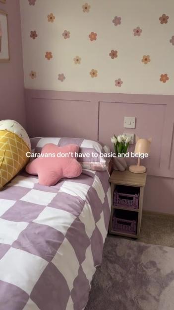 Renovated caravan bedroom with lavender walls, checkered bedding, and flower decals.