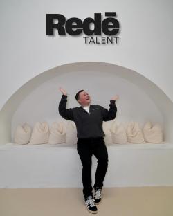 A man celebrating in front of a Redé Talent sign.