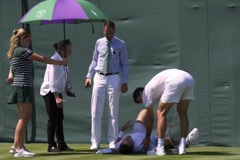 Injured tennis player Hamad Medjedovic receiving attention on the court.