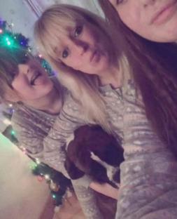 A mother and her two daughters cuddling a dog.