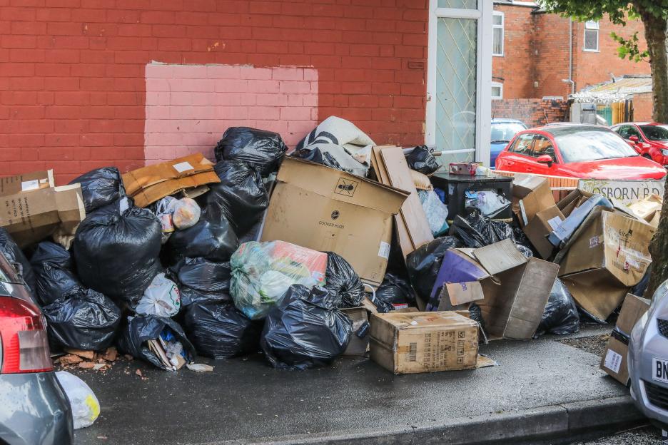 Pile of rubbish and cardboard boxes on a city street.