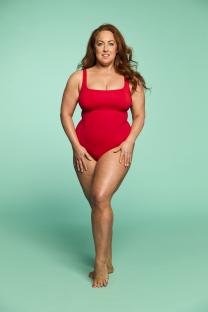Woman in red swimsuit against teal background.