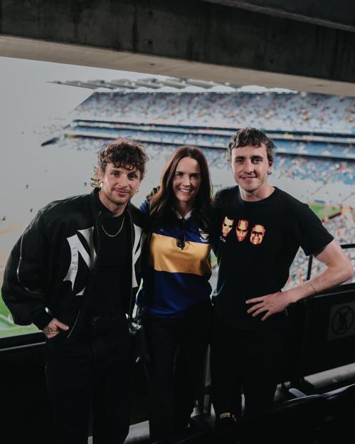 Three people posing for a photo in a stadium.