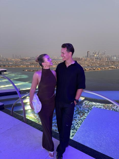 Couple smiling at each other by a rooftop pool overlooking Dubai.